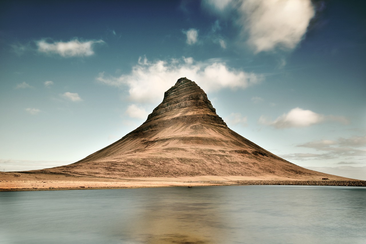 A mountain peak before a blue lake and on a blue sky